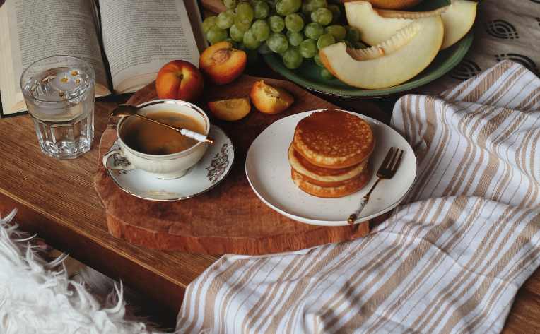 living the hygge lifestyle with coffee, food and a book in a cozy nook